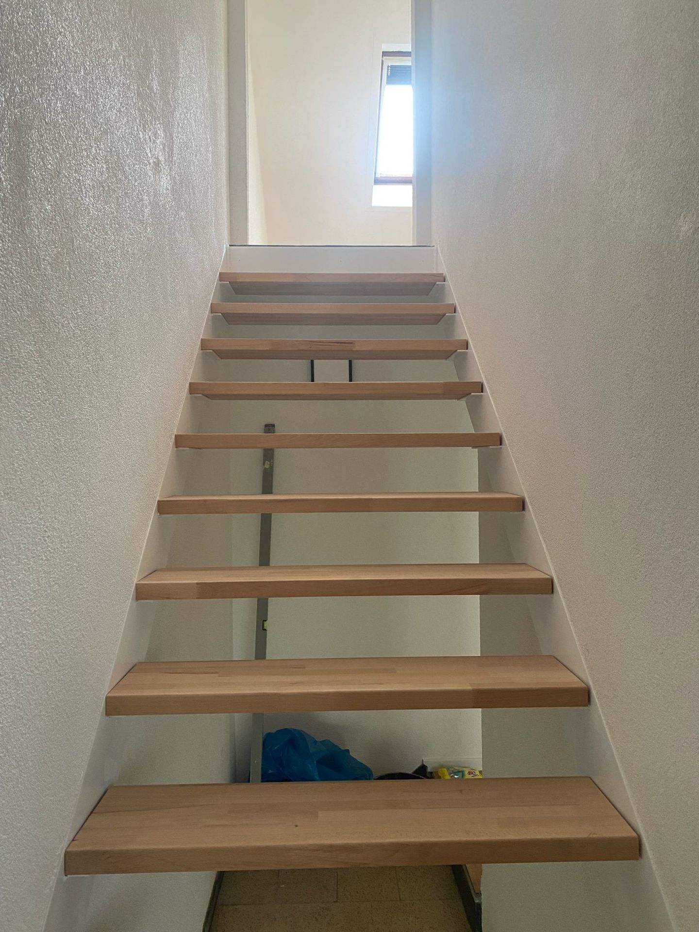 Treppe mit hellen Holzstufen und frisch verputzten, weiß gestrichenen Wänden